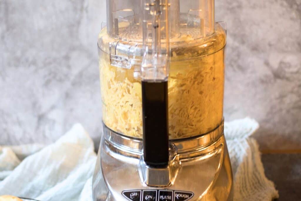 food processor with shredded potato inside.
