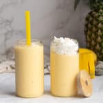 two mango pineapple smoothies in glass jars