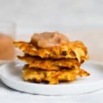 three latkes stacked on a plate with a dollop of applesauce