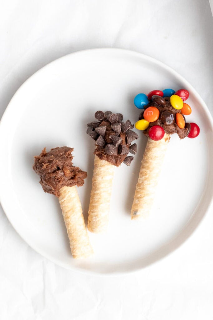 three wafer cookies dipped in brownie batter with toppings.