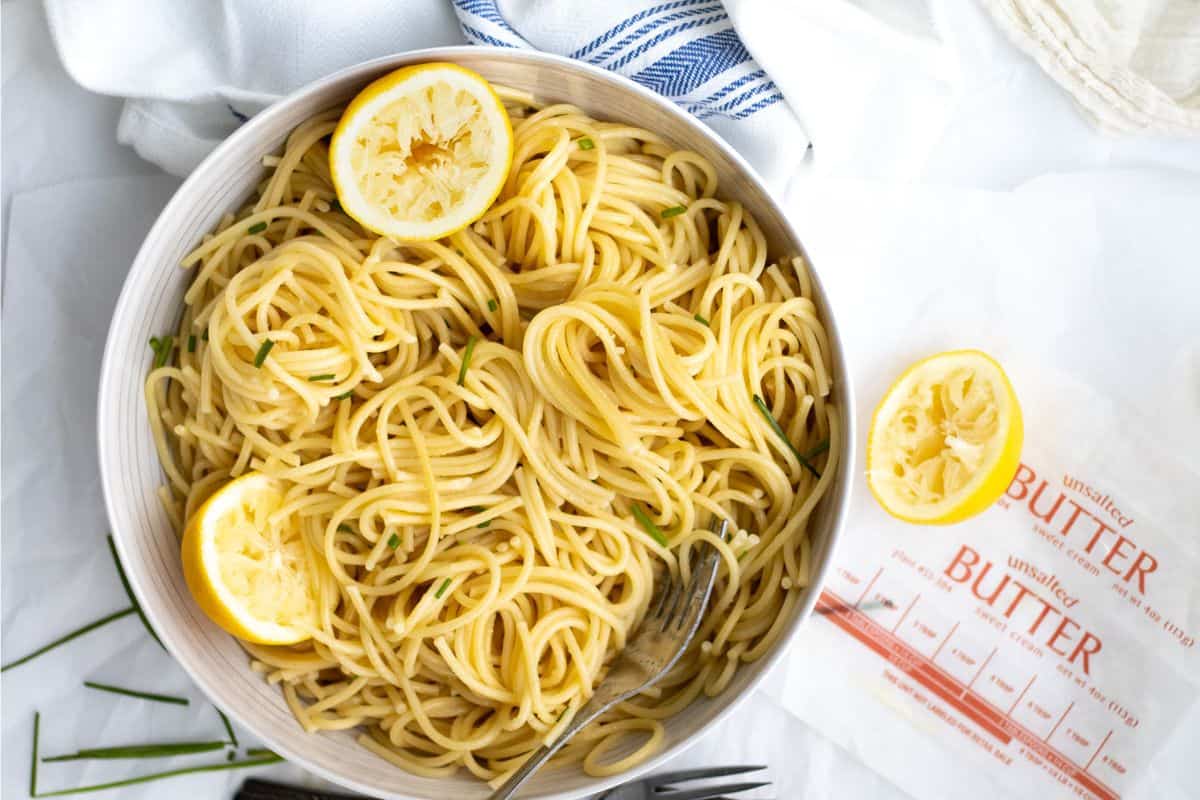 lemon butter pasta in a bowl with squeezed lemons.