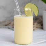 pina colada smoothie with a lime wedge in a glass