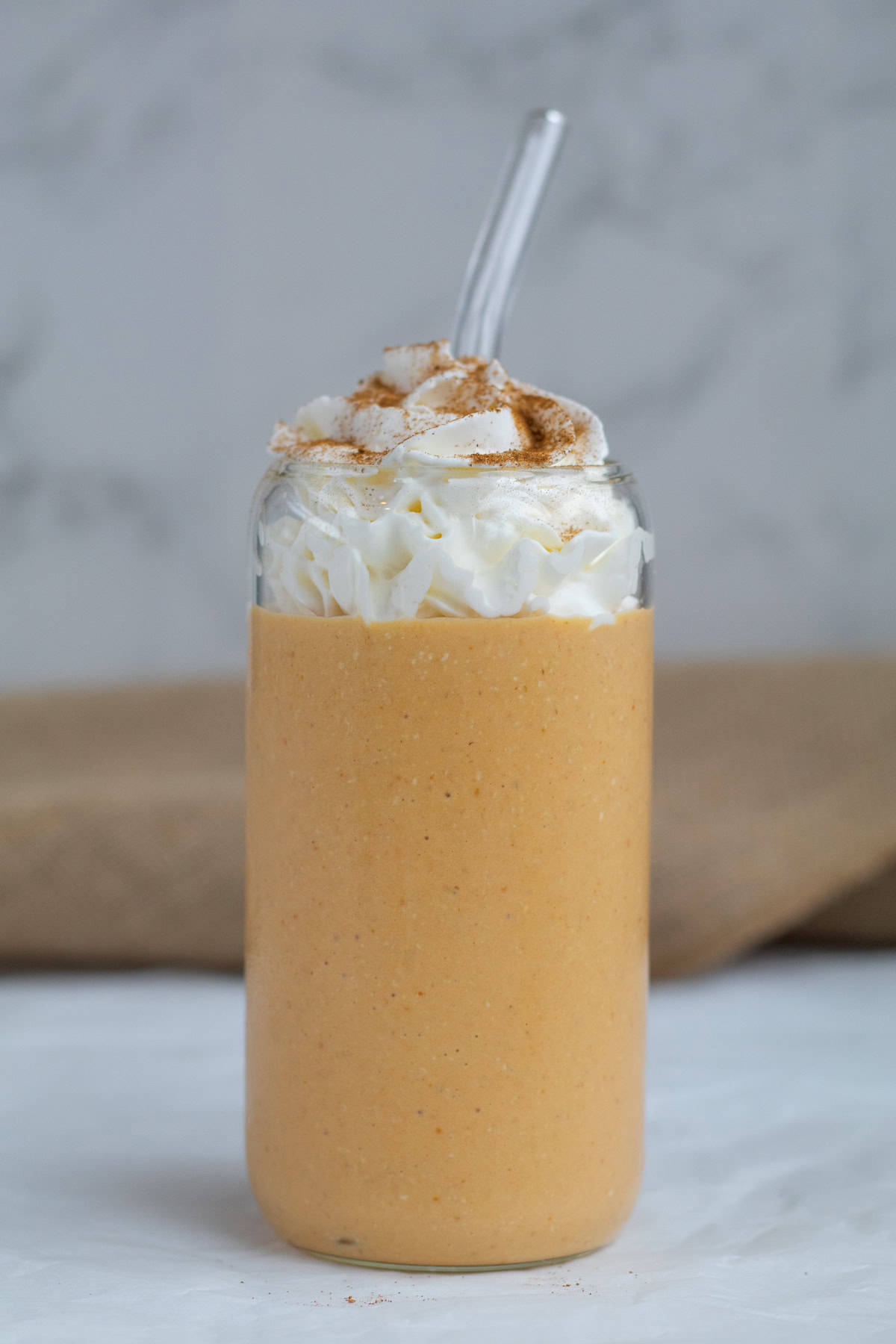 pumpkin pie smoothie with whipped cream and glass straw.