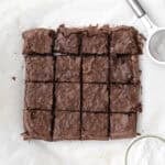 brownies right out of a square pan on parchment paper cut into 16 pieces