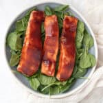 three pieces of bbq salmon on a bed of spinach