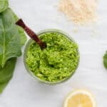 spinach pesto in a small mason jar with a wooden sppon