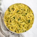 spinach pesto pasta swirled in a white serving bowl