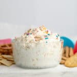 funfetti dip in a glass bowl with sprinkles surrounded by dipping options