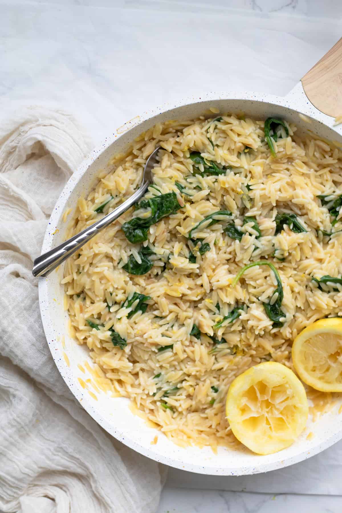 pan of lemon orzo with spinach and serving spoon