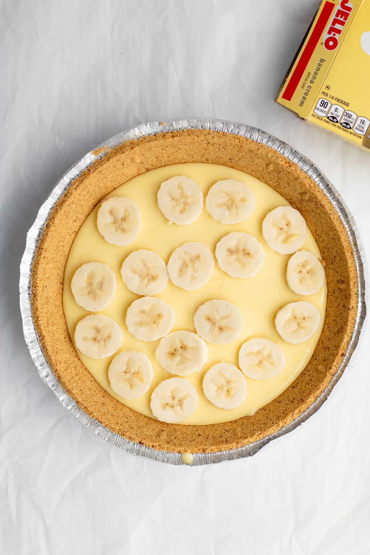 sliced banana on top of banana pudding in a pie shell