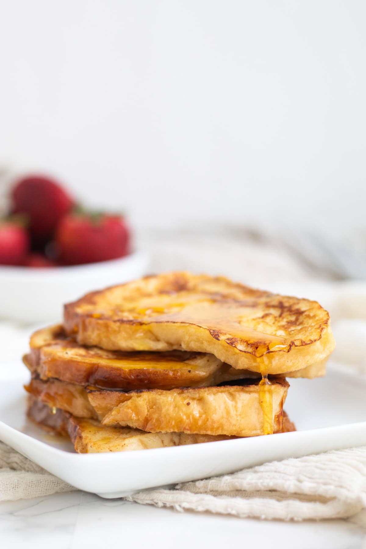 french toast stacked with strawberries in the background
