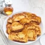 challah french toast on a white plate with syrup behine