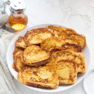 challah french toast on a white plate with syrup behine