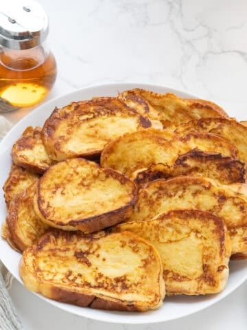 challah french toast on a white plate with syrup behine