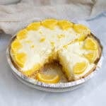 lemon pie with a slice cut out garnished with lemons