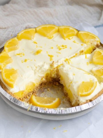 lemon pie with a slice cut out garnished with lemons