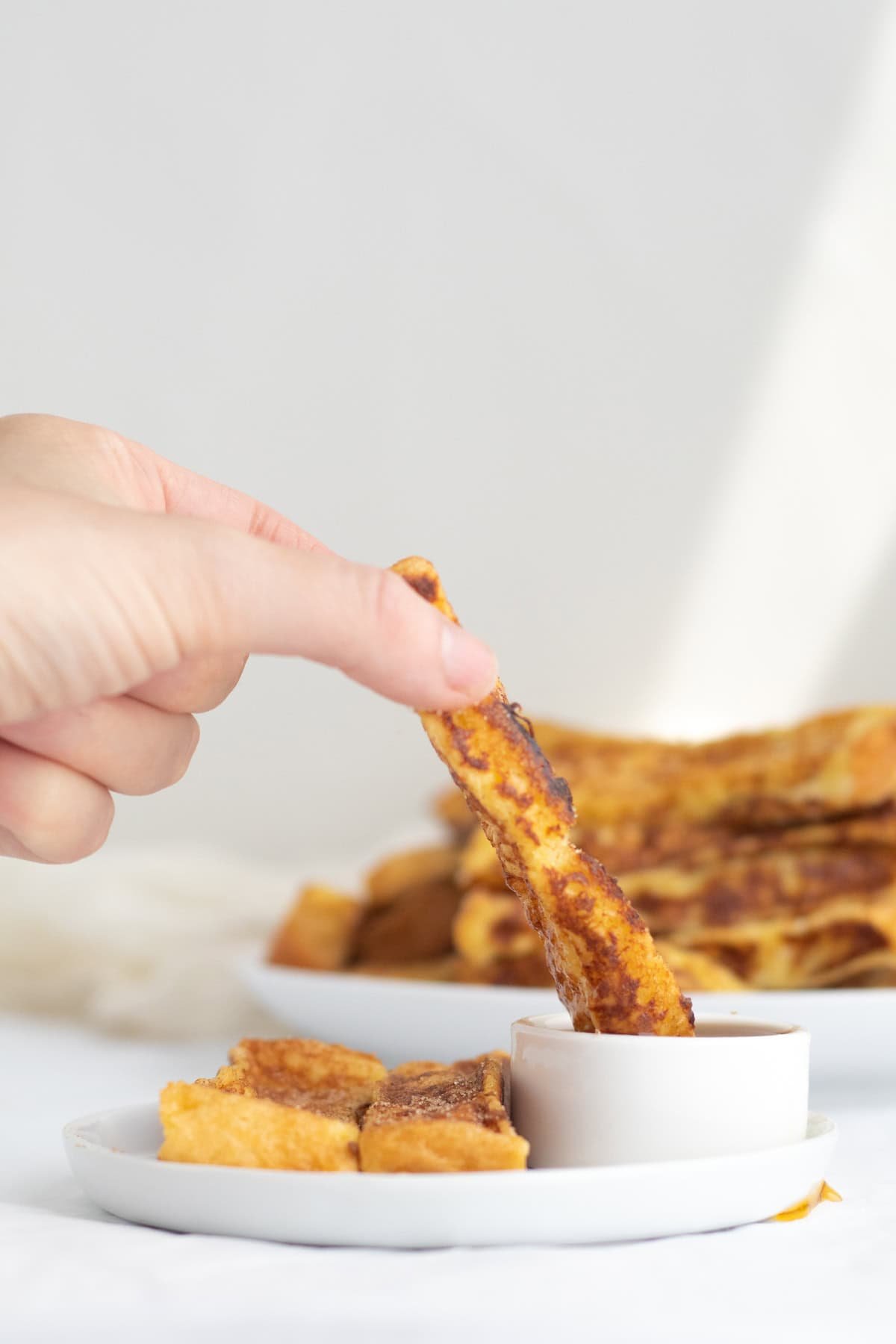 french toast sticks being dipped into maple syrup