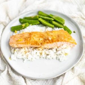 miso butter salmon on a white plate over rice with edamame