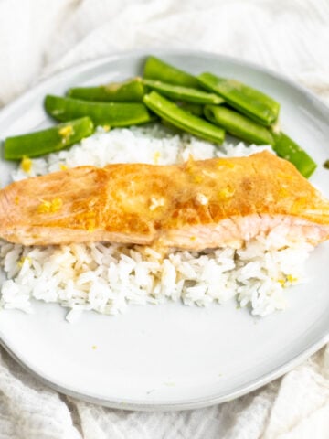 miso butter salmon on a white plate over rice with edamame