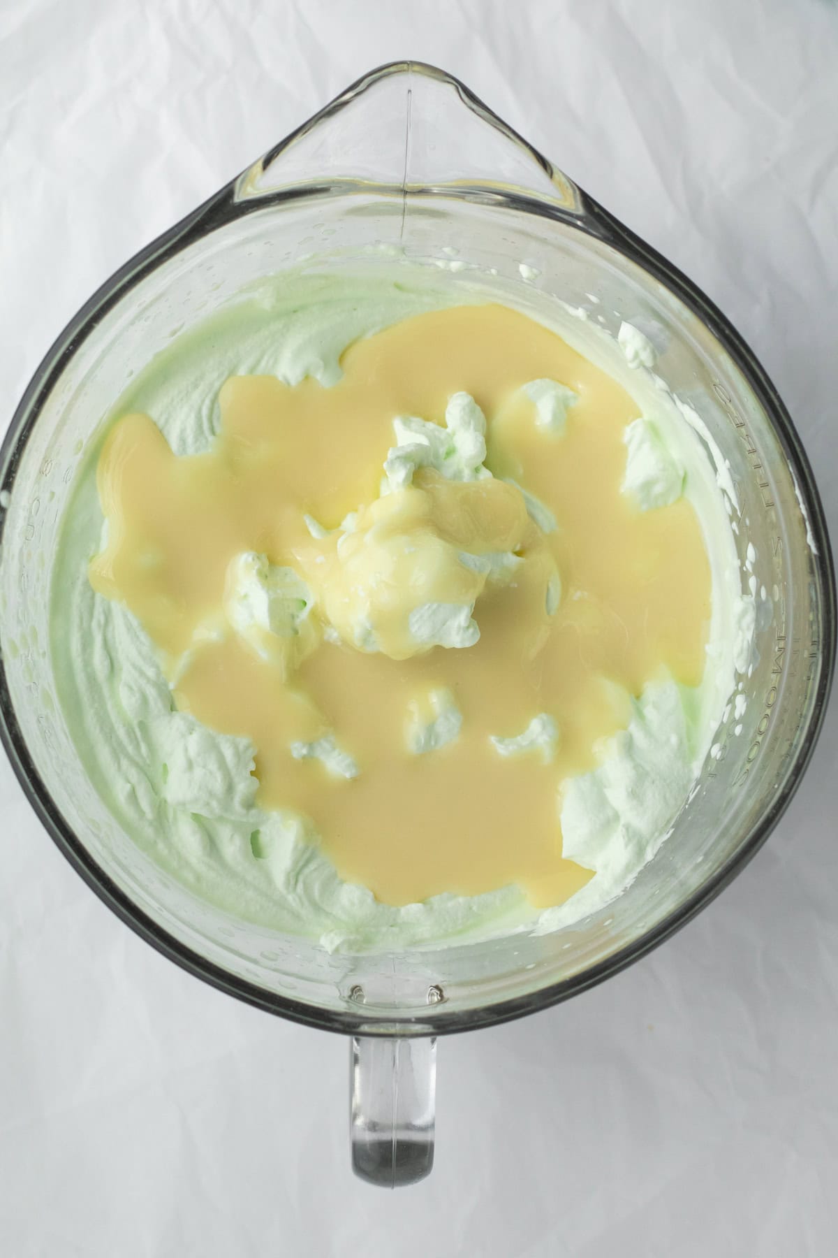 sweetened condensed milk being added to whipped cream base