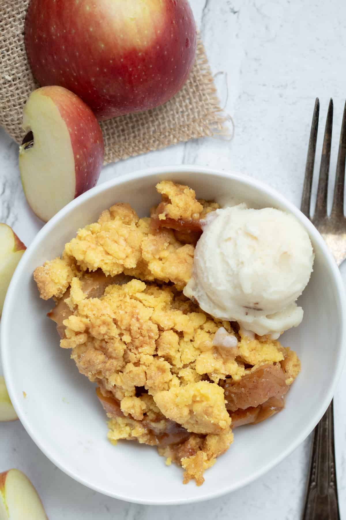 apple dump cake in a white bowl with a scoop of ice cream