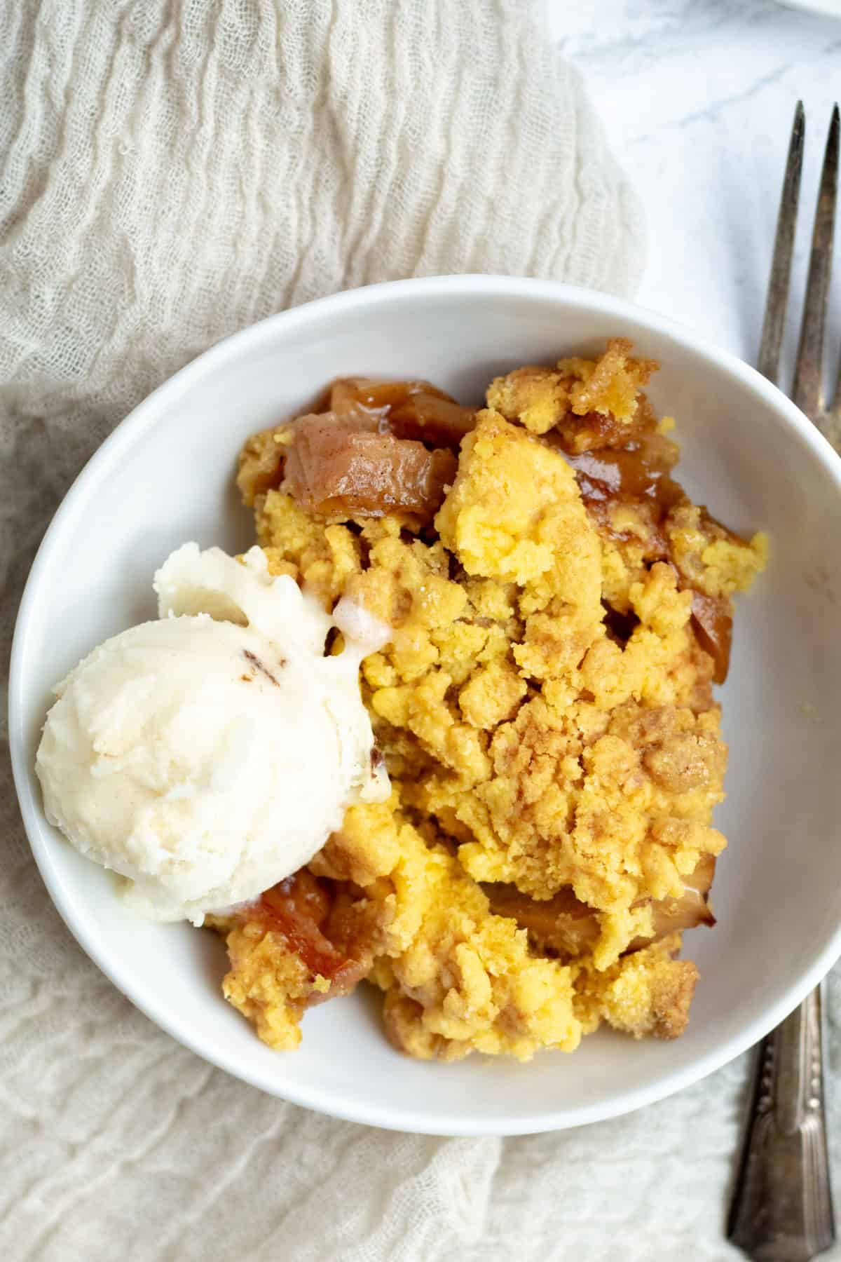 apple dump cake in a bowl with a scoop of ice cream