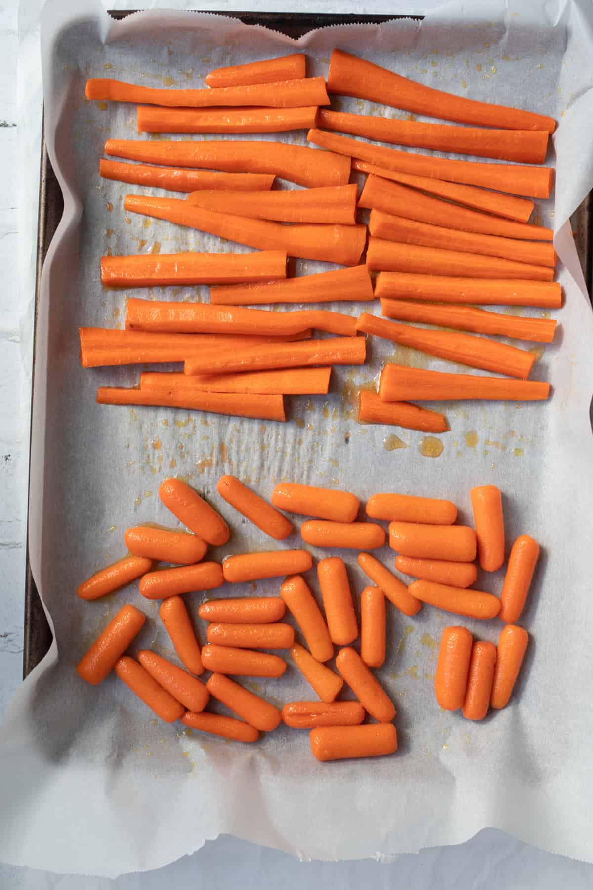 baby carrots and big carrots on a parchment lined baking sheet.