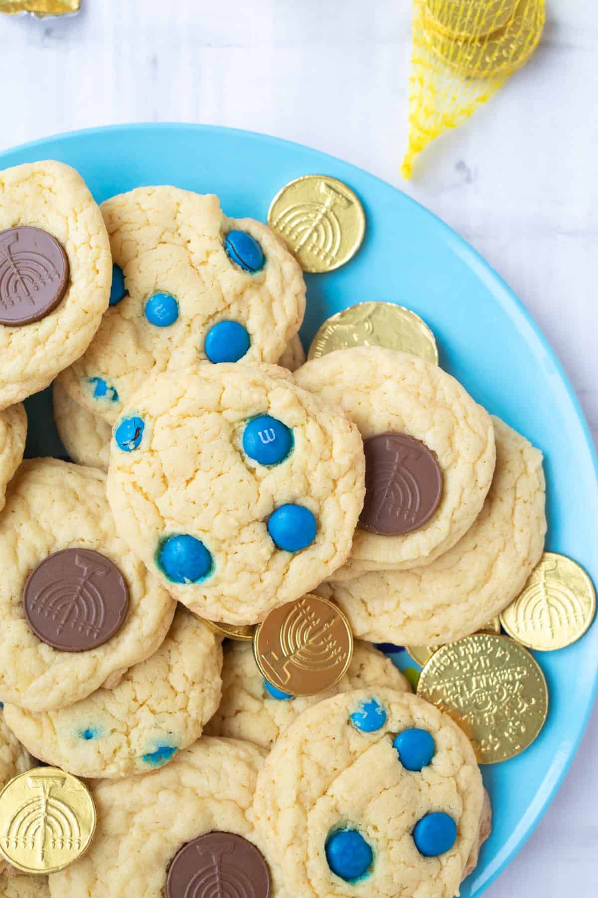 hanukkah cookies on a blue plate with gelt in bags.