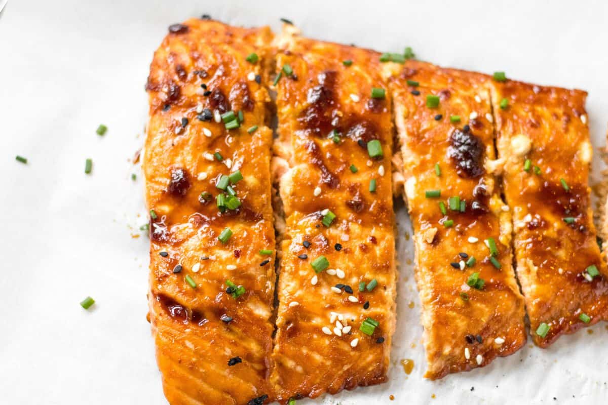 Baked Sesame ginger on a parchment lined baking sheet garnished with sesame seeds and scallions.