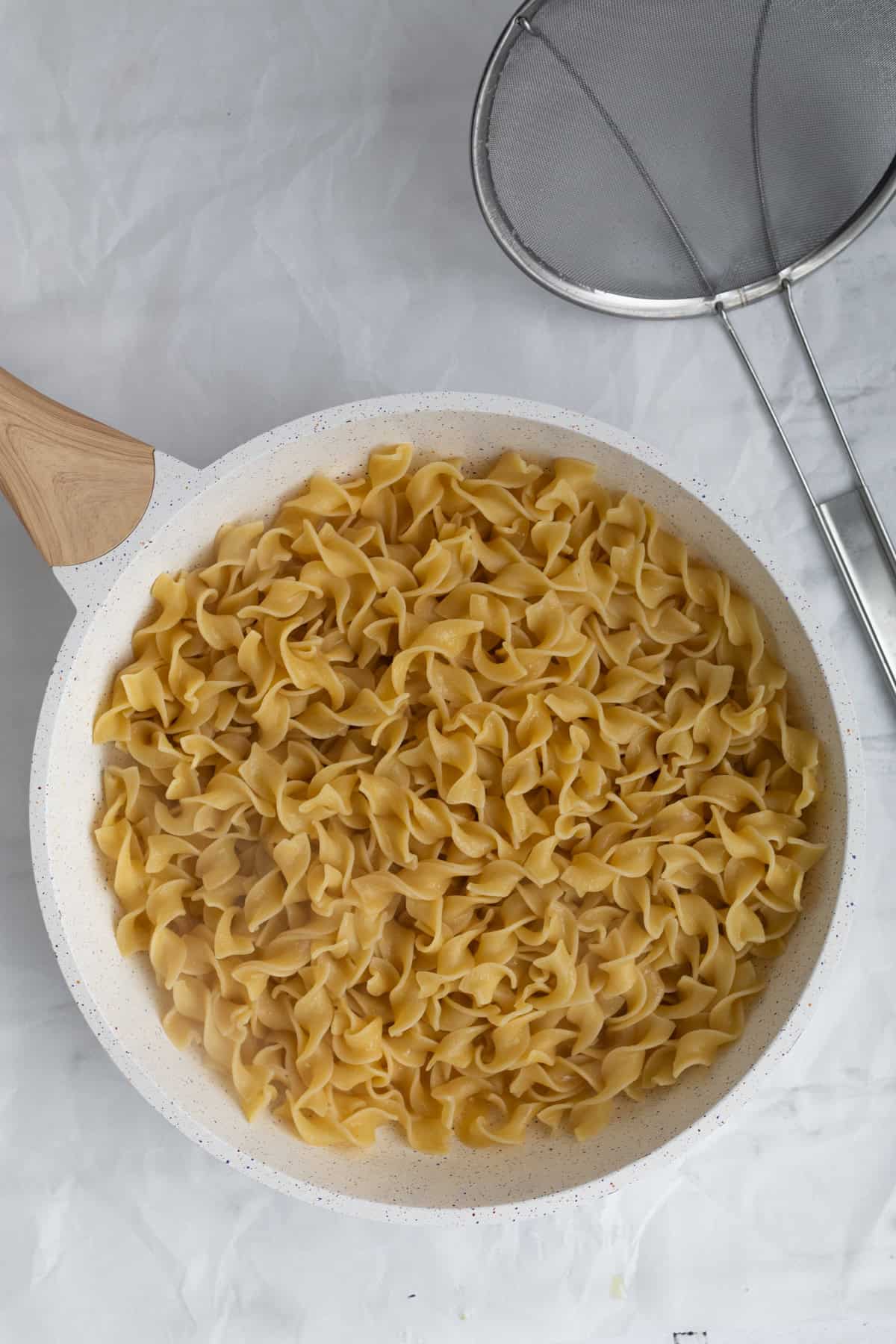 drained noodles added to the melted butter.
