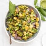 Sheet pan pesto gnocchi in a serving dish with a basil garnish.