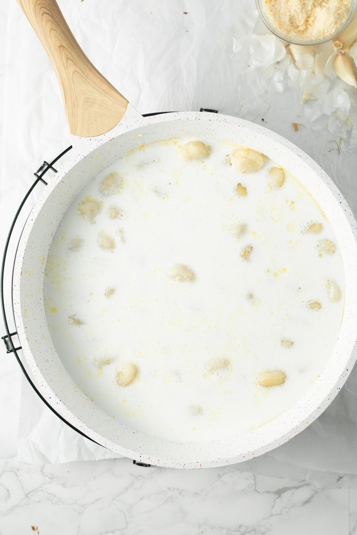 Gnocchi, milk, water, butter, garlic in a pan cooking.
