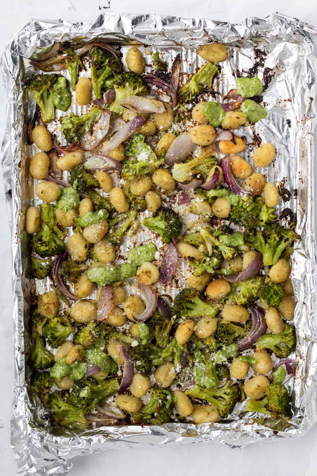cooked sheet pan gnocchi with pesto on a foil lined sheet pan.