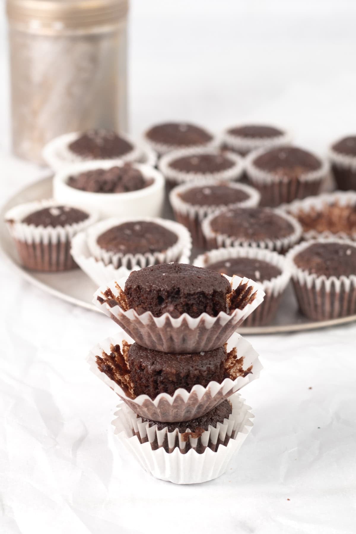 three stacked brownie bites with a tray of brownies behind.