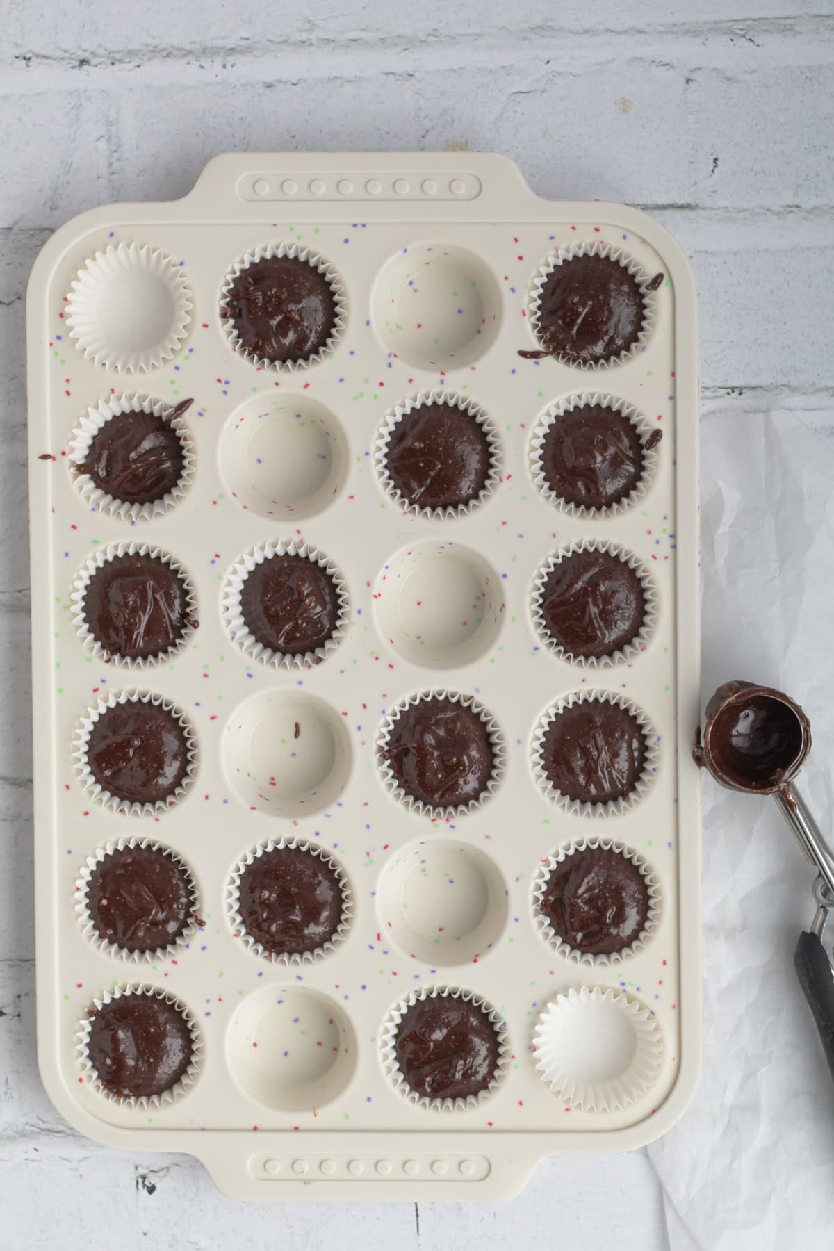 Cookie scoop filling mini muffin tin.