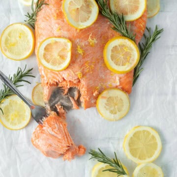baked lemon butter salmon with lemon rounds on parchment paper.