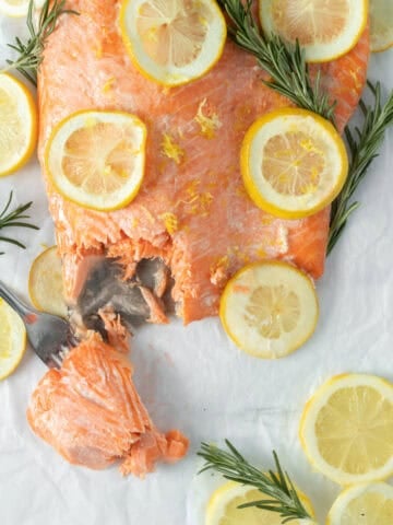baked lemon butter salmon with lemon rounds on parchment paper.