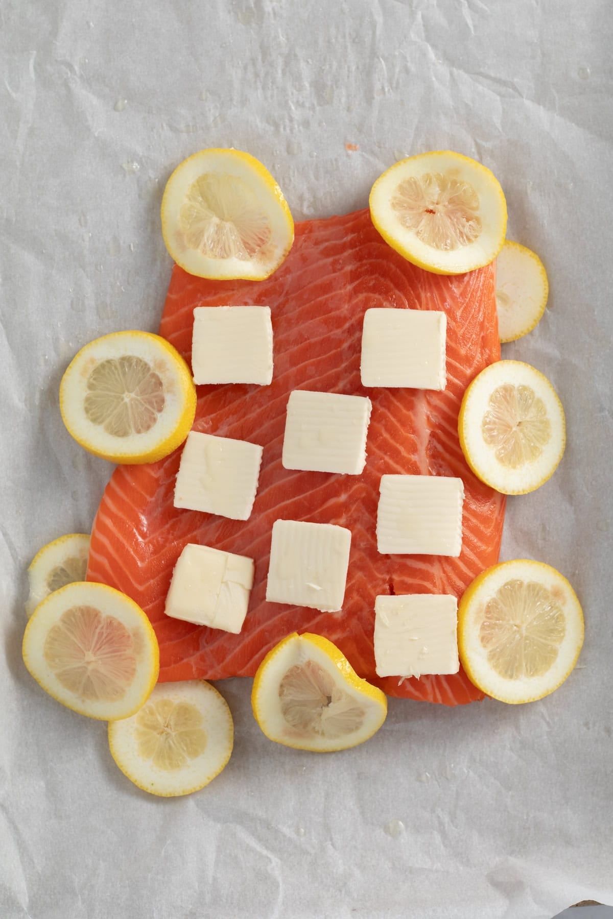 butter and lemons on raw salmon.