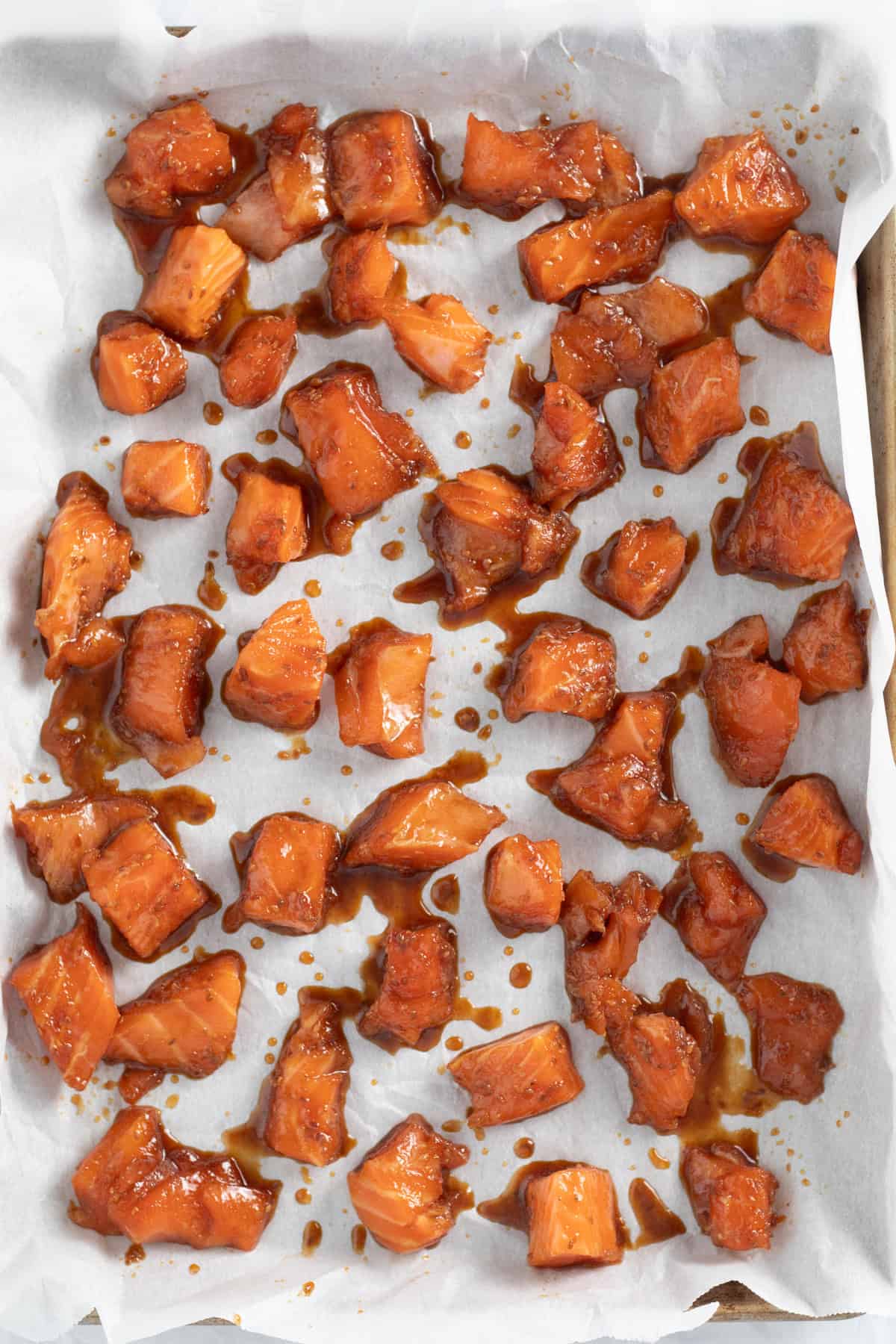 marinated raw salmon on a parchment lined sheet tray.
