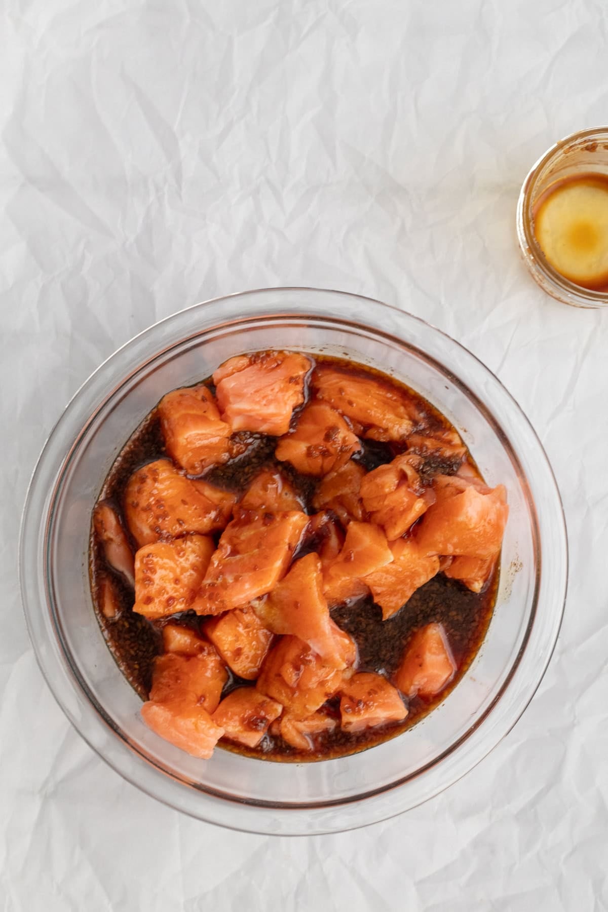 salmon marinating in a glass bowl.