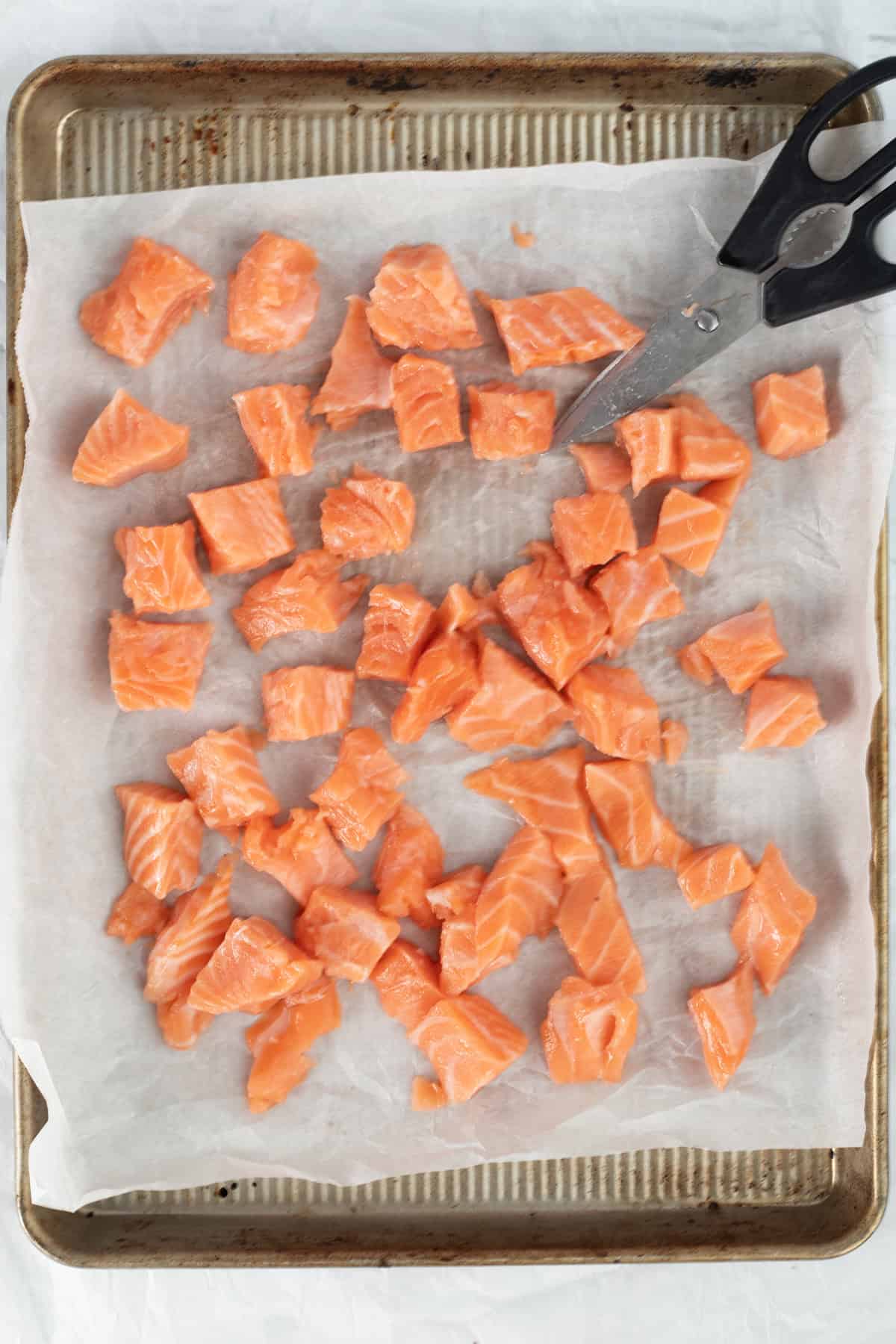 cut pieces of salmon on a sheet tray.
