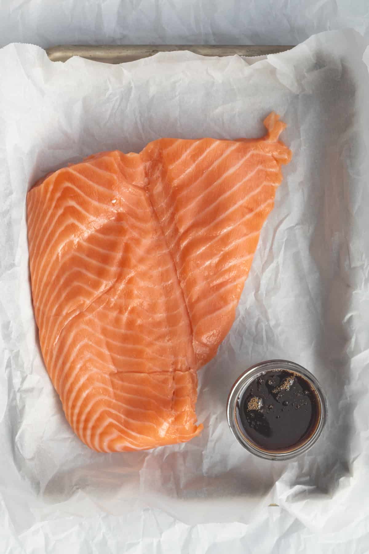 salmon and soy sauce on a parchment lined sheet pan.