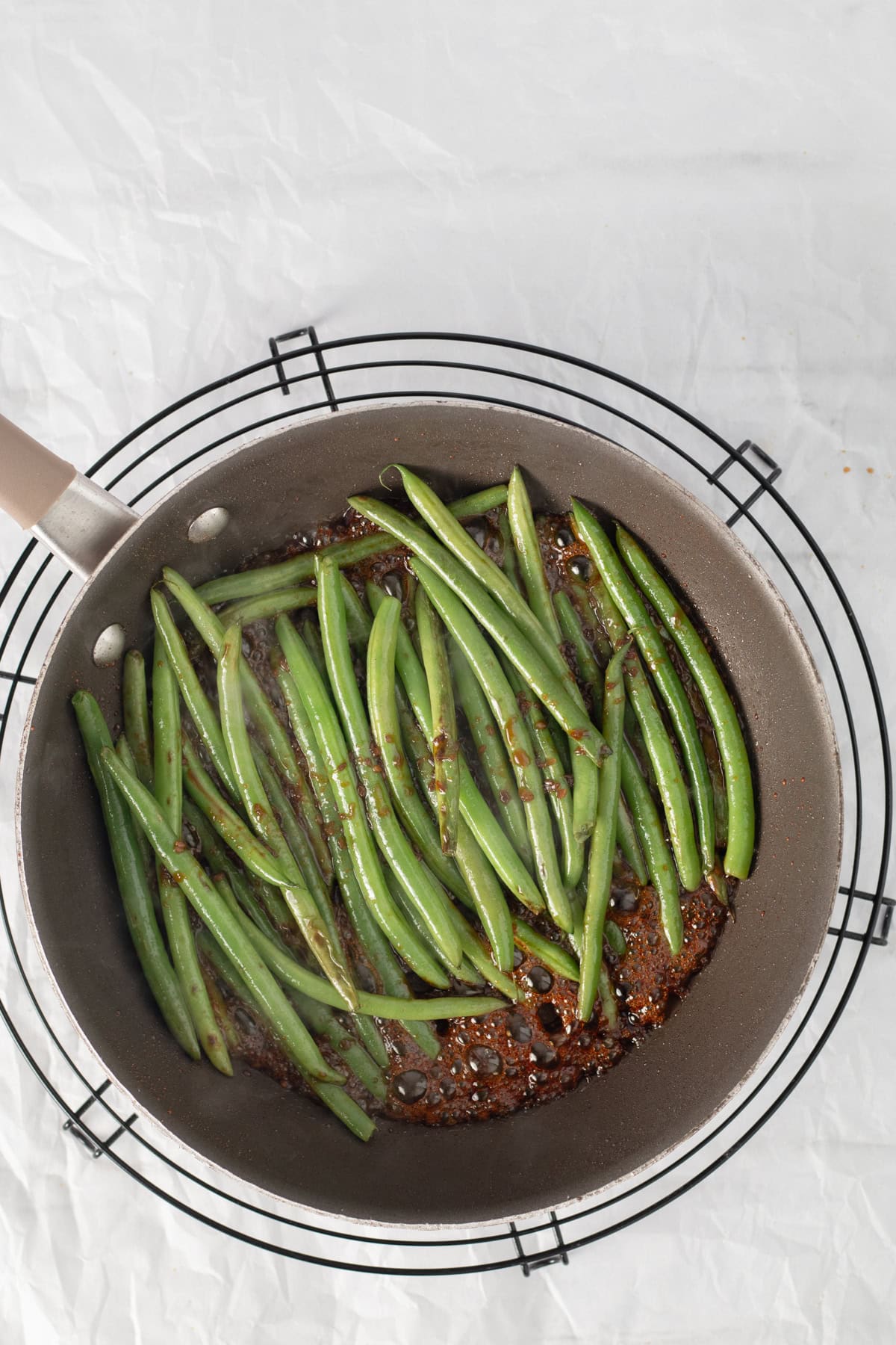 green beans cooking in teriyaki sauce in a frying pan.