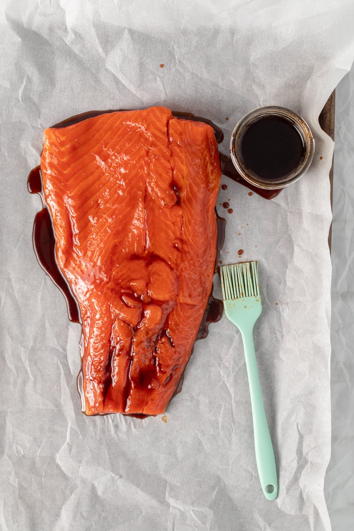 teriyaki sauce being brushed onto a piece of salmon.