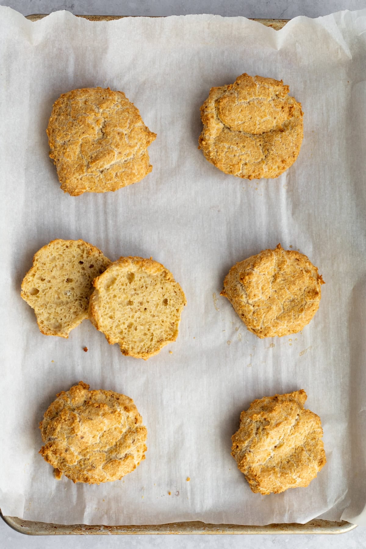 matzo meal rolls on a parchment lined sheet tray with one cut open.