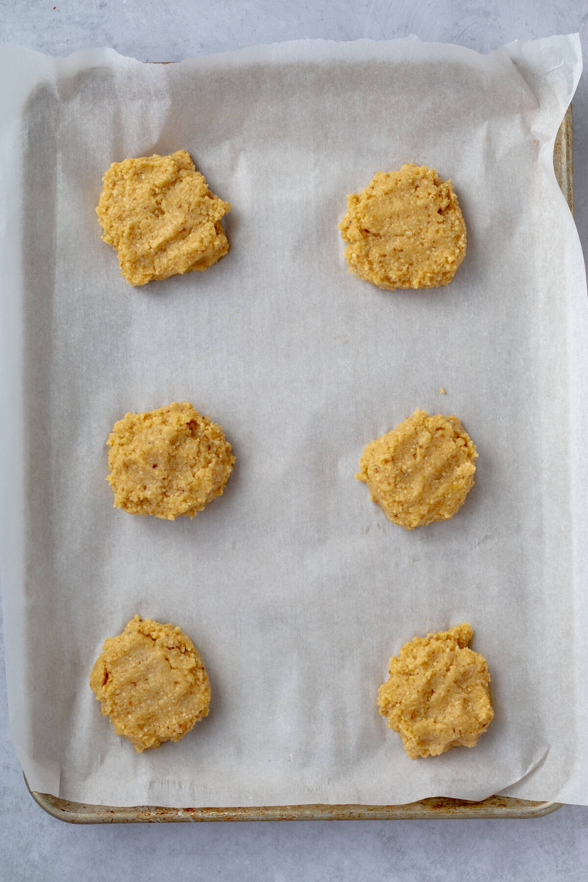 6 raw passover rolls on a parchment lined sheet tray.
