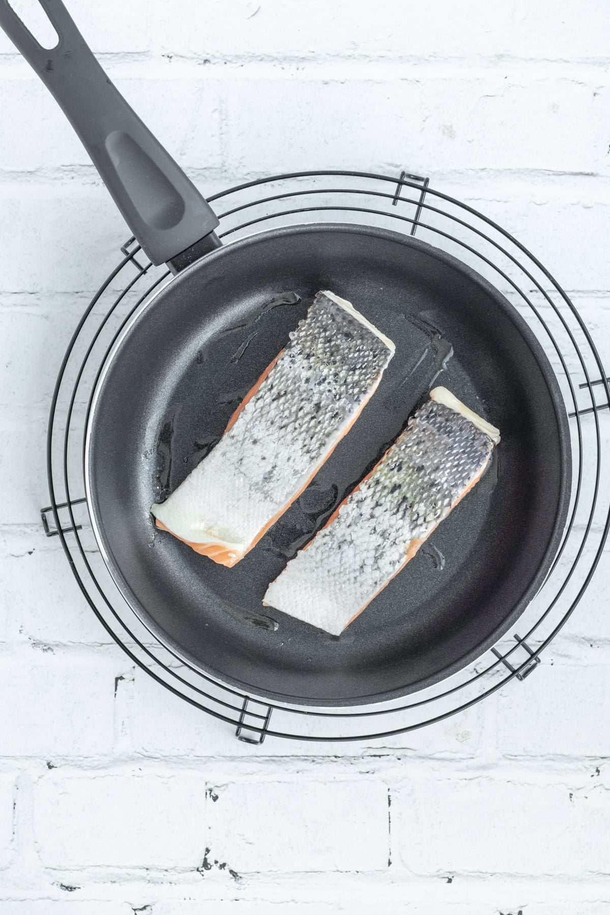 salmon being seared in a frying pan.