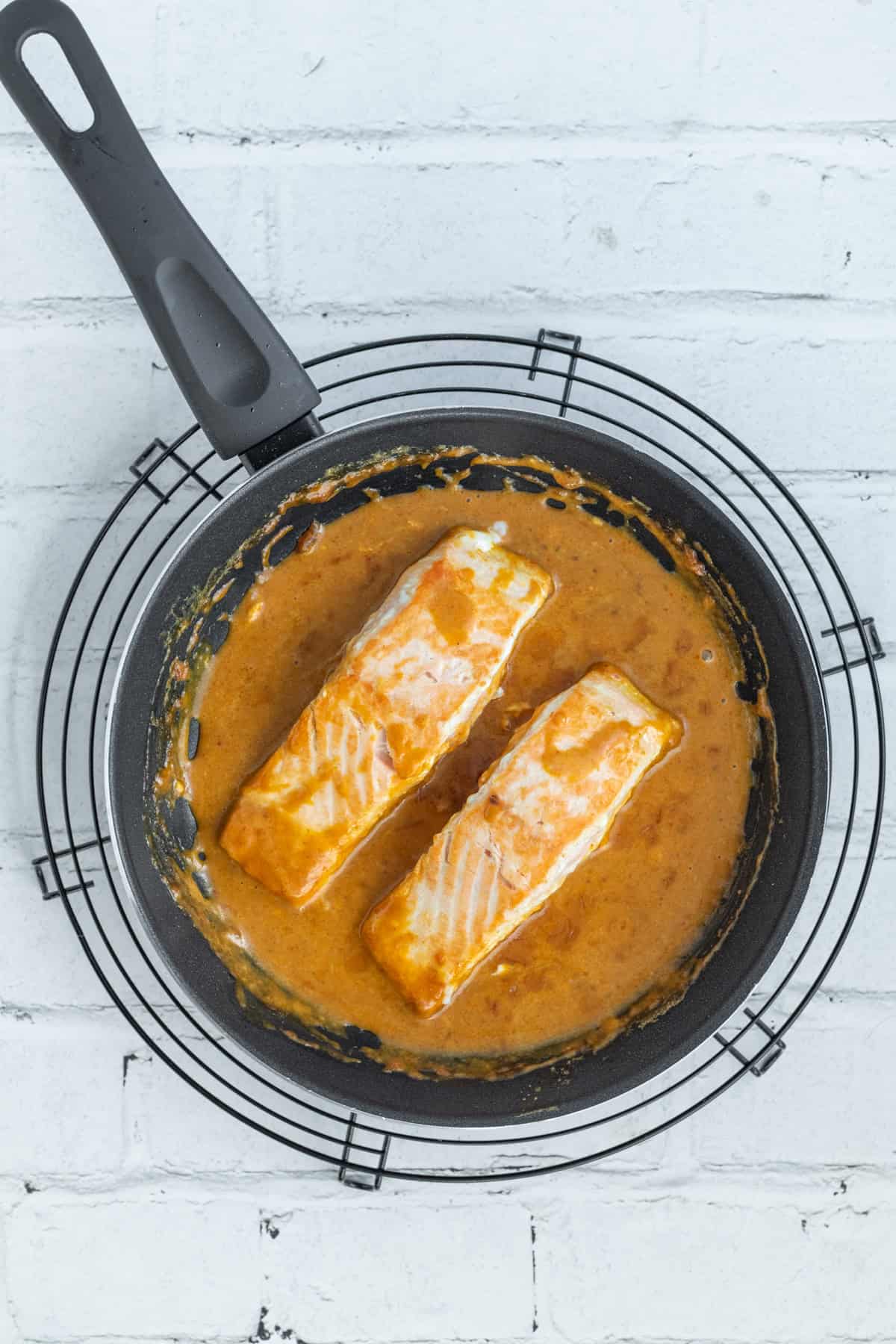 Salmon cooking in red curry sauce.