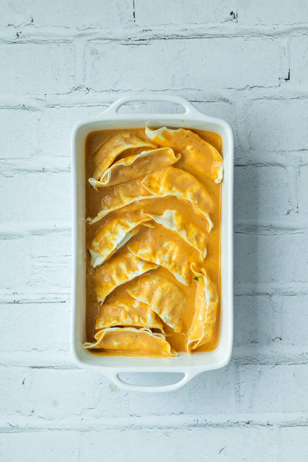 frozen potstickers with curry sauce in a baking dish.