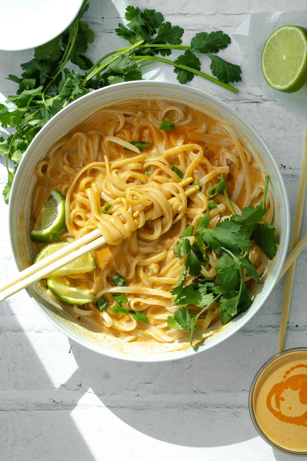 thai red noodles with lime and cilantro and chopsticks.